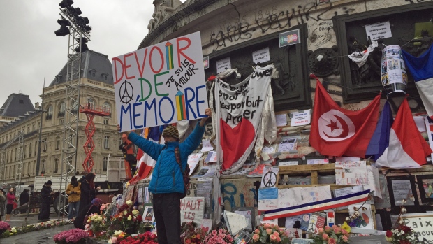 A man holds a sign that reads 'Duty to Remember&#39 at the statue in Place de la République in Paris during Sunday's memorial ceremonies