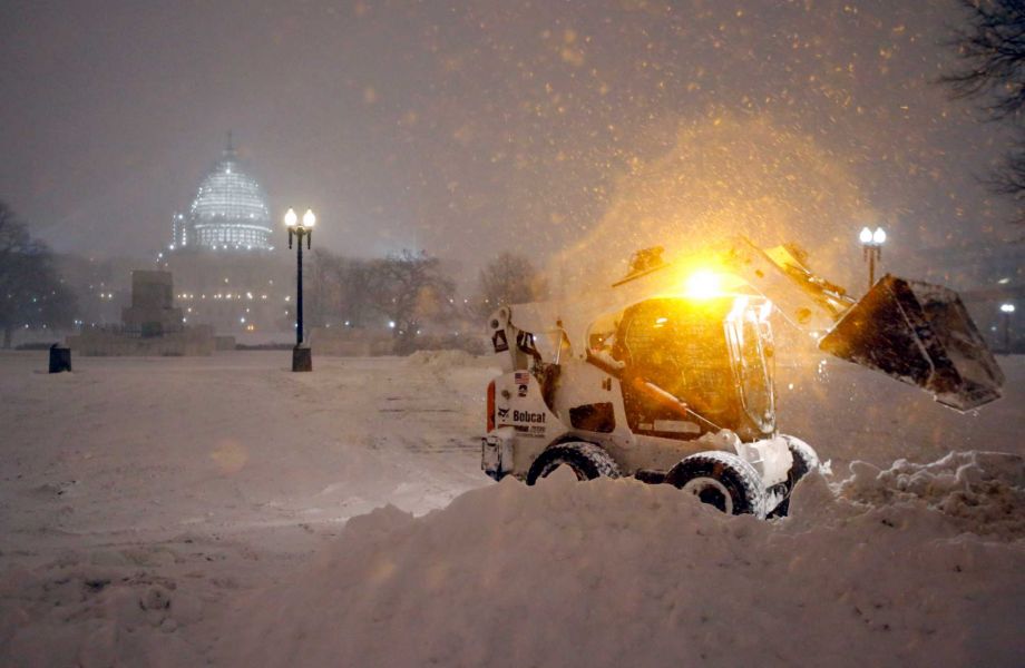 A bobcat piles up snow in front of the U.S. Capitol as the snow continues to fall Friday Jan. 22 2016 in Washington