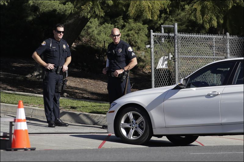 Two Pasadena police officers inspect a vehicle on Colorado Blvd on the route of the Rose Parade in Pasadena Calif. Thursday