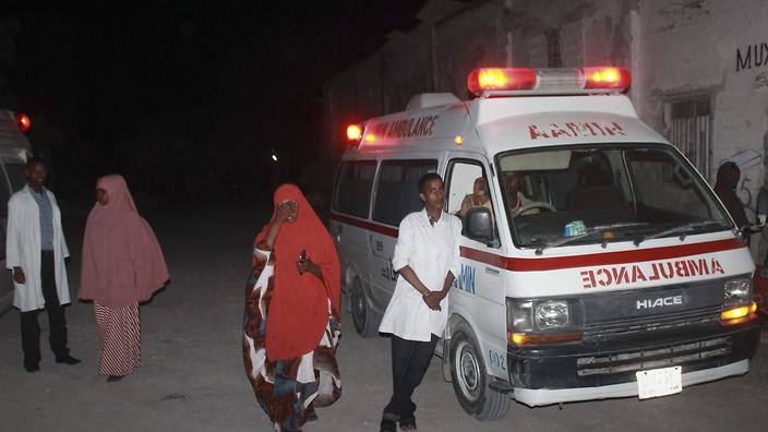 Ambulance workers stand by near the Lido beach where gunmen exploded a car bomb and opened fire at a restaurant in Mogadishu Somalia