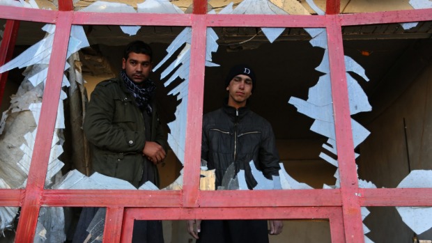 An Afghan shopkeeper watches from the broken window of his shop near the site of suicide car bomb attack in Kabul Afghanistan last month