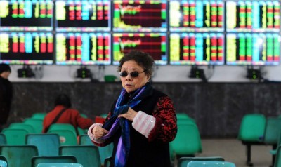 An investor makes her way in front of screens showing stock market movements in a stock firm in Wuhan China on Friday