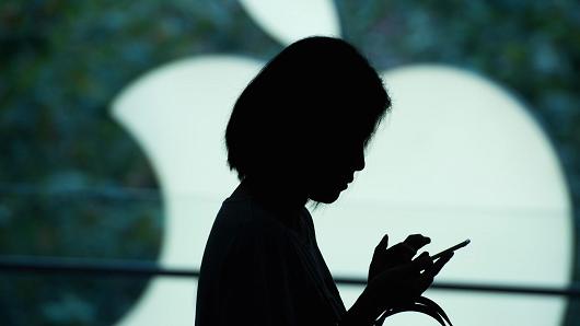 A customer uses her smartphone at an Apple store in Shanghai