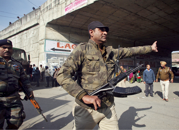 A security personnel asks people to move away from the area outside the Indian Air Force base at Pathankot in Punjab on January 3