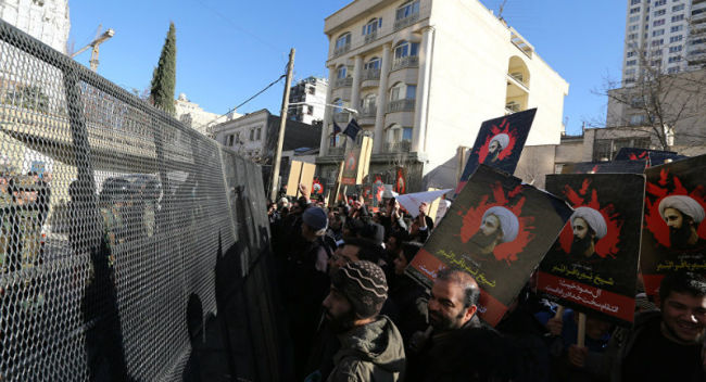 Protestors hold posters of Nimr al Nimr aloft during a demonstration in Baghdad