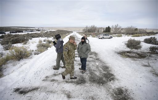 Members of the group occupying the Malheur National Wildlife Refuge headquarters stand guard along a roadside Monday Jan. 4 2016 near Burns Ore. The group calls itself Citizens for Constitutional Freedom and has sent a'demand for redress to local