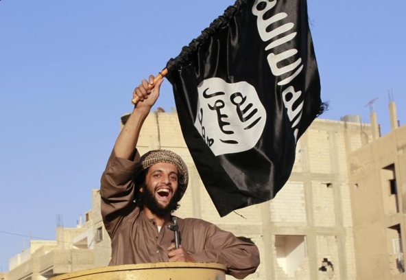 A militant Islamist fighter waving a flag cheers as he takes part in a military parade along the streets of Syria's northern Raqqa province