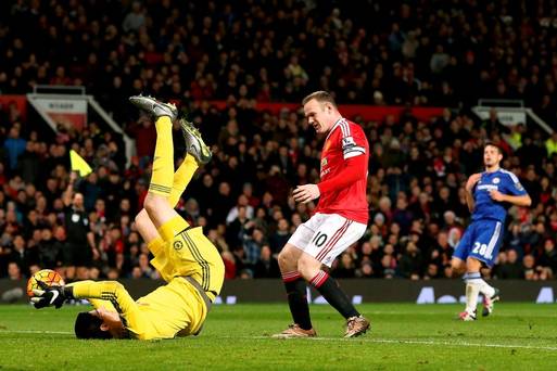 Chelsea goalkeeper Thibaut Courtois holds onto the ball after making a save as Manchester United's Wayne Rooney looks