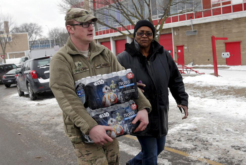 Michigan National Guard Staff Sergeant William Phillips assists a Flint resident with bottled water at a fire station in Flint Michigan