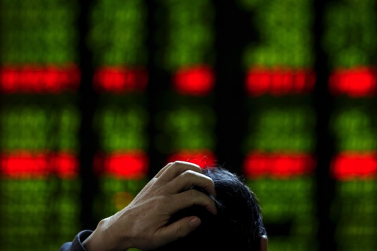 A man scratches his head as he checks the stock prices on an electronic board at a brokerage house in Beijing