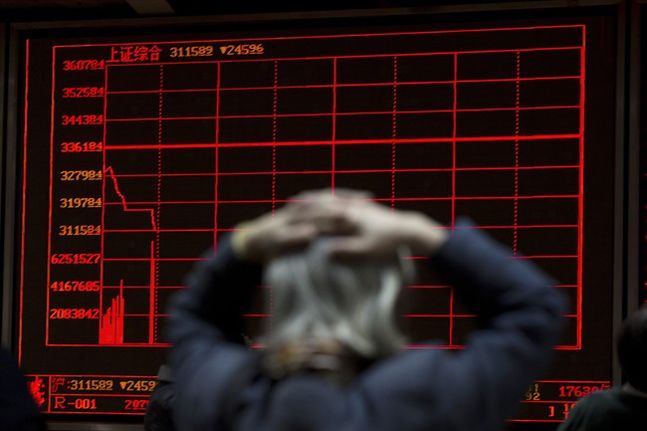 A woman reacts near a display board showing the plunge in the Shanghai Composite Index at a brokerage in Beijing China Thursday Jan. 7 2016. Chinese stocks nosedived on Thursday triggering the second daylong trading halt of the week and sending other