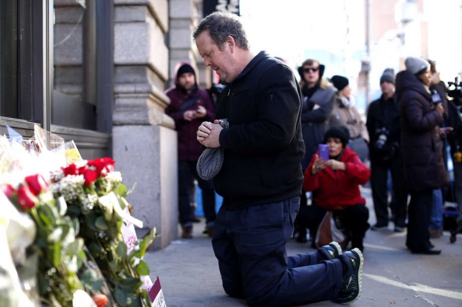 A man prays at a memorial outside the residence of David Bowie in New York City on Monday. Bowie died at the age of 69 from cancer prompting tributes from stars and fans alike