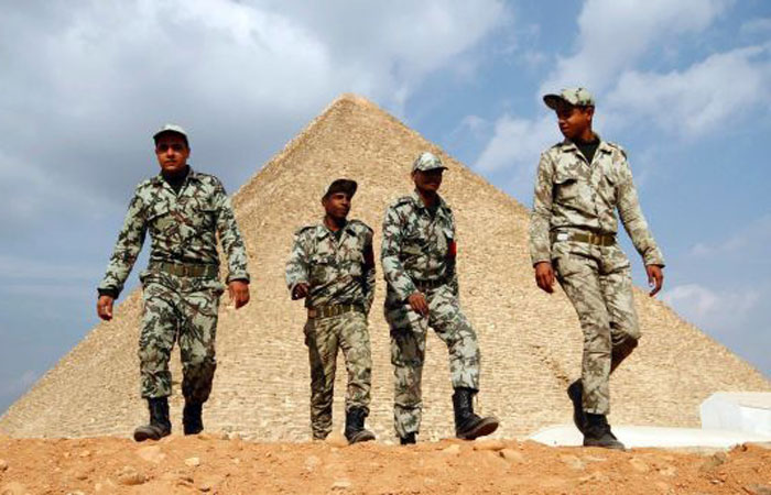 Egyptian soldiers walk in front of the Great Giza pyramids on the outskirts of Cairo