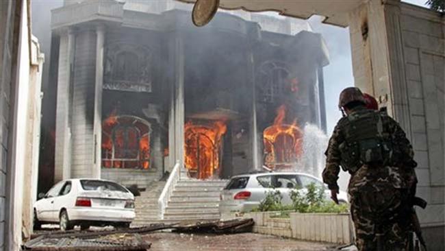 Afghan security forces watch a house burn at the site of a clash between militants and security forces at the Indian Consulate in Herat in Afghanistan