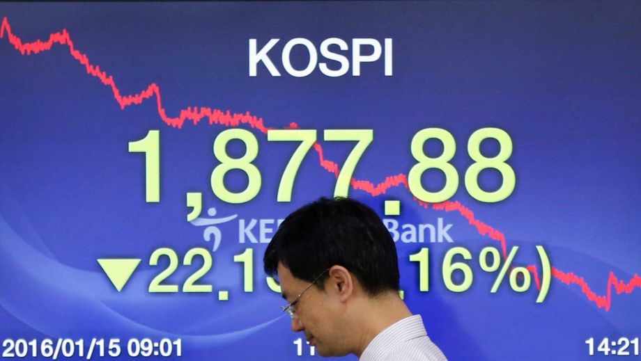 A currency trader walks by the screen showing the Korea Composite Stock Price Index at the foreign exchange dealing room in Seoul South Korea Friday Jan. 15 2016. After opening higher Asian stock markets were lower Friday with China's Shangha