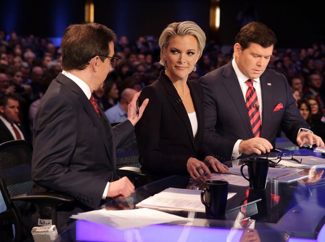 Moderators Chris Wallace pats the shoulder of Megyn Kelly as they wait with Bret Baier for the beginning of the Fox News GOP debate in Iowa