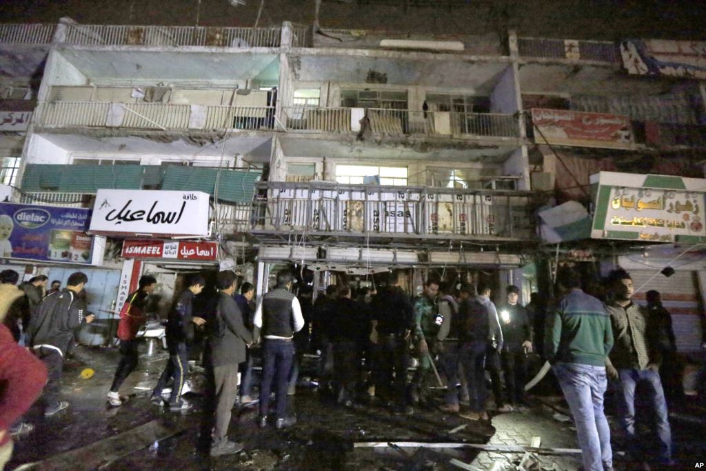 People gather in front of the mall in Baghdad Iraq on Jan. 11 2016. Gunmen stormed into the mall Monday spraying bullets at shoppers before blowing themselves