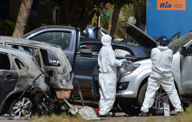 Forensics experts inspect a car outside Splendid Hotel in Ouagadougou on Monday following the jihadist attack