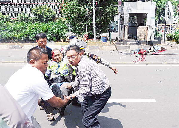 People carry an injured police offi cer near the site where an explosion went off at a police post, in Jakarta Indonesia on Jan 14. Attackers set off explosions at a Starbucks cafe in a bustling shopping area in Indonesia’s capital and