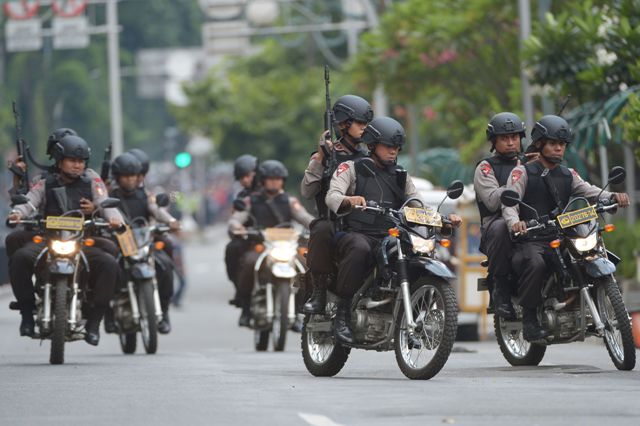 Indonesian policemen arrive to enter a building as armed men exchange shots with police in Jakarta