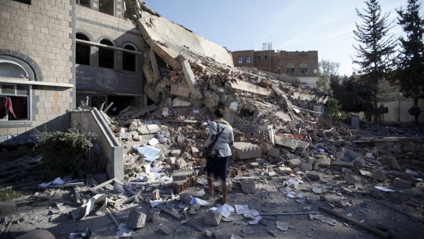 A Houthi militant walks on the rubble of the Chamber of Trade and Industry headquarters after it was hit by a Saudi-led air strike in Yemen's capital Sanaa