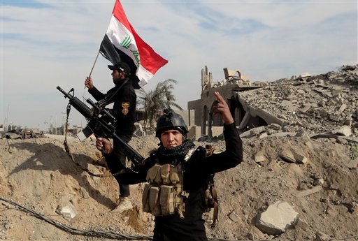 Iraqi security forces raise an Iraqi flag near the provincial council building in central Ramadi 70 miles west of Baghdad. Iraqi military forces on Monday retook a strategic government complex in the