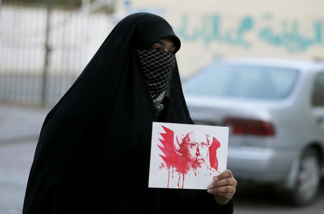 A protester holds an image depicting Saudi Shi'ite cleric Nimr al Nimr as she protests against his execution by Saudi authorities in village of the Sanabis west of Manama Bahrain