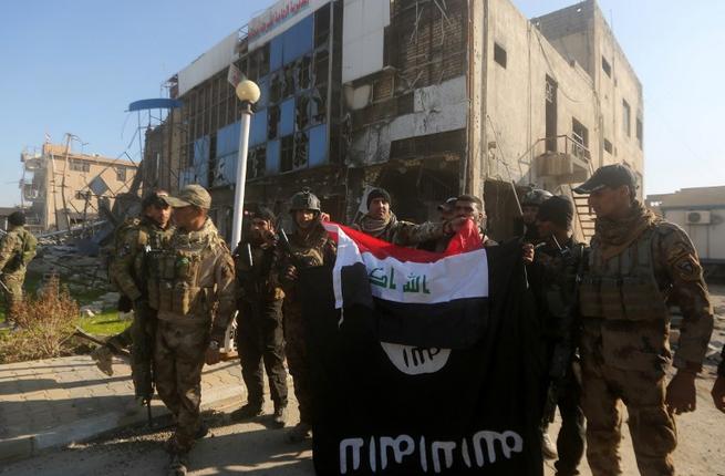 Iraqi security forces place the Iraqi flag above the Islamic State group flag as they pose for