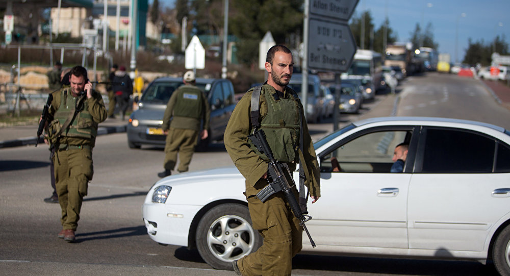 Israeli soldiers stand guard at the Gush Etzion junction in the Israeli occupied West Bank on the main road between Jerusalem and Hebron