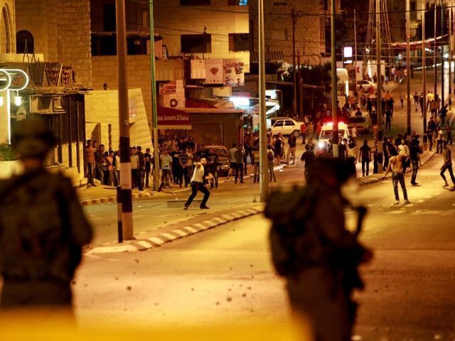 Palestinian protesters throw stones towards an Israeli military observation tower at a section of the separation barrier to the main entrance of the West bank city of Bethlehem