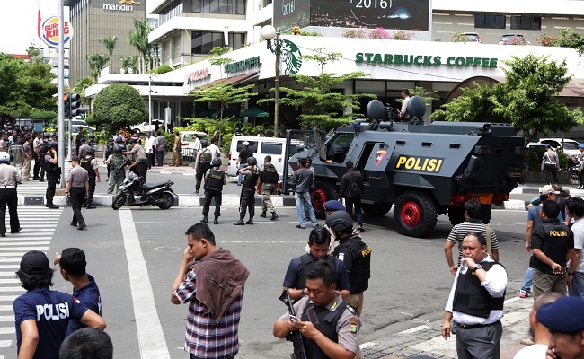 Police officers stand guard outside a Starbucks cafe near where an explosion went off in Jakarta Indonesia Thursday Jan. 14 2016. Attackers set off explosions at a Starbucks cafe in a bustling shopping area of downtown Jakarta and waged gun-battles wit