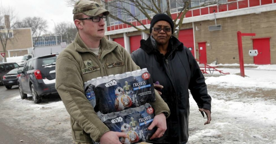 Michigan National Guard Staff Sergeant William Phillips assists a Flint resident with bottled water at a fire station in Flint Michigan earlier this month