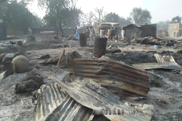 People walk past burned-out houses following Sunday’s attack