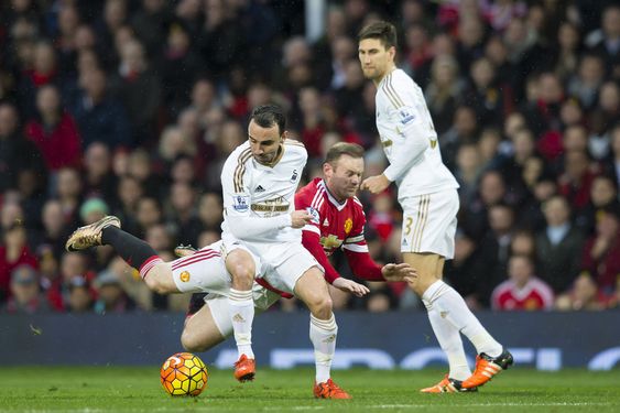 Rooney centre is brought down by Swansea City's Leon Britton left as Federico Fernandez looks on during the English Premier League soccer match between Manchester United and Swansea City at Old Trafford Stadium Manche