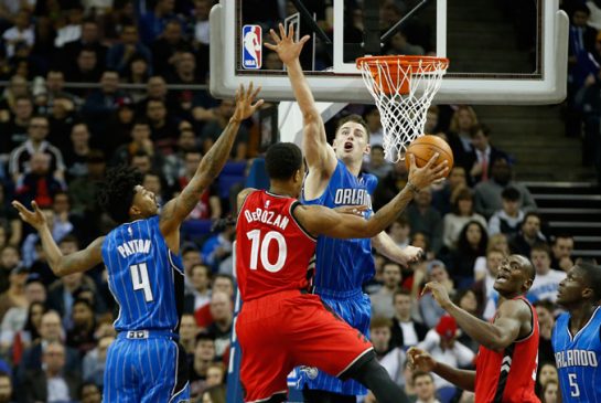 Toronto Raptors guard De Mar DeRozan center goes for the basket as Orlando Magic's Jason Smith defends during the first half of an NBA basketball game at the O2 arena in London Thursday Jan. 14 2016. Raptors won the game 106-103