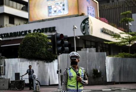 An Indonesian policeman stands guard in front of the damaged Starbucks building in Jakarta on Friay