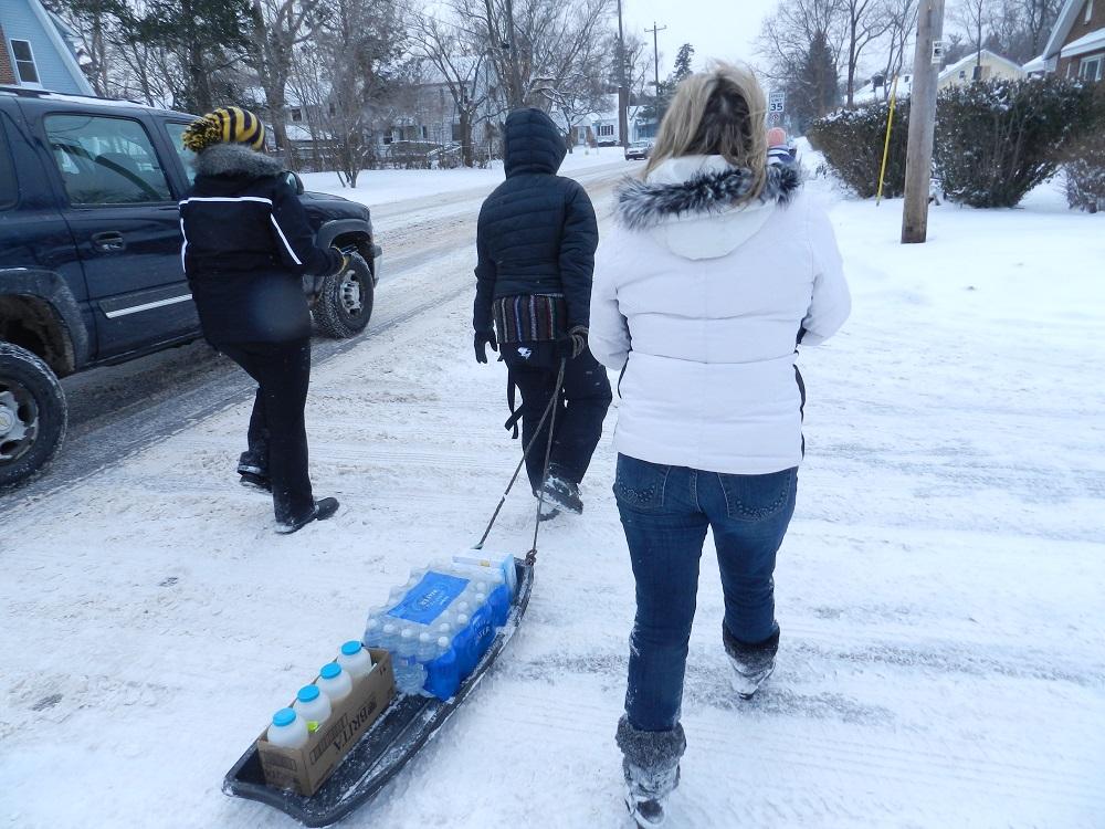 Volunteers pull a sled with bottled water and lead testing kits as they go from house to house on Flint's north side