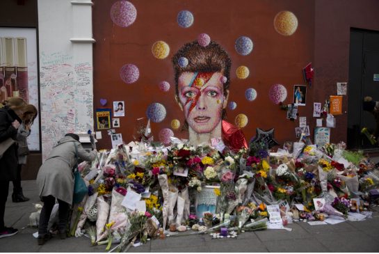 People flowers around a mural of British singer David Bowie in south London Thursday