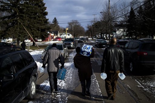 Flint residents Marcus Shelton from left Roland Young and Darius Martin walk on an ice-covered street as they retrieve free water on Sunday Jan. 17 2016 at Heavenly Host Full Gospel Baptist Church in Flint Mich. Flint's water became contaminat