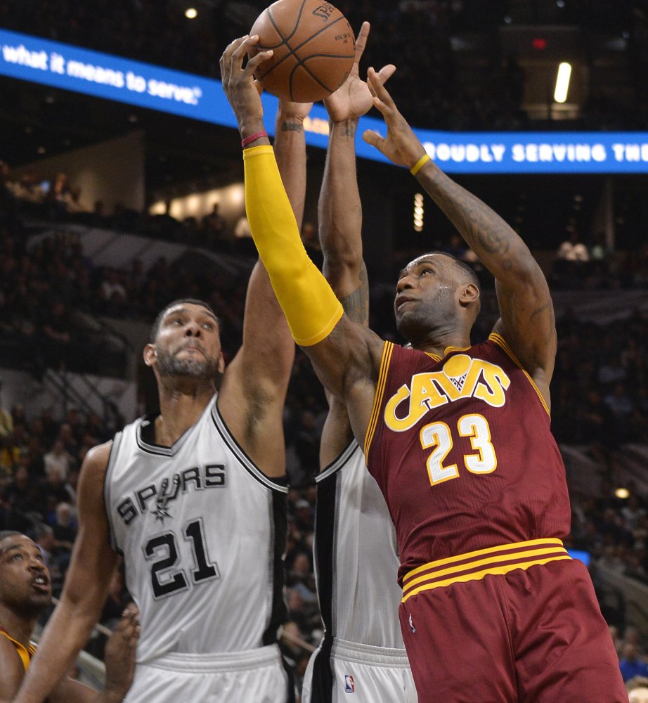 LeBron James of the Cleveland Cavaliers heads to the basket Thursday night while trying to avoid a block by Tim Duncan of the San Antonio Spurs during the first half of the Spurs’ 99-95 victory at home