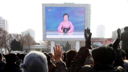 North Koreans watch a news broadcast on a video screen outside Pyongyang Railway Station