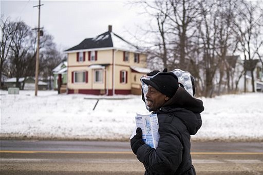 Flint resident Charles Chatmon carries a free water filter and case of water away from a fire station where members of the Michigan National Guard helped distribute supplies to aid in the city's water crisis on Wednesday Jan. 13 2016 in Flint Mic