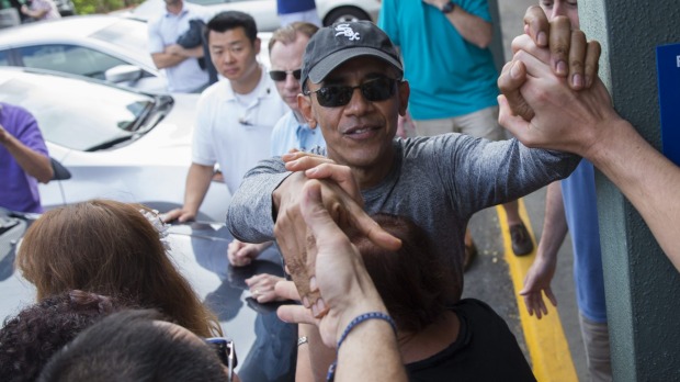 President Barack Obama shakes hands with bystanders during a visit to Island Snow a store for athletic clothing that has a shave-ice machine during his family holiday in Hawaii on Sunday