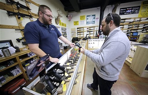 Mike Howse left helps David Foley as he shops for a handgun at the Spring Guns and Ammo store Monday Jan. 4 2016 in Spring Texas. President Barack Obama defended his plans to tighten the nation's gun-control restrictions on his own insisting Mo