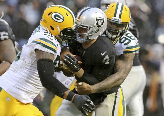 Oakland Raiders quarterback Derek Carr is tackled by Green Bay Packers outside linebacker Julius Peppers left and outside linebacker Mike Neal during the second half of an NFL football game in O