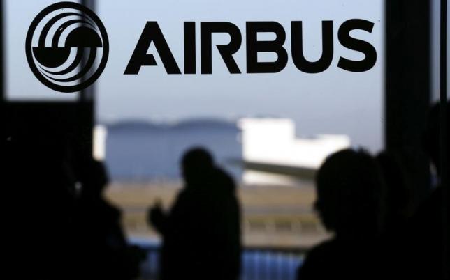 People are silhouetted past a logo of the Airbus Group during the Airbus annual news conference in Colomiers near Toulouse