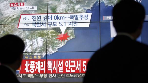 People in Seoul walk by a screen showing the news reporting on an earthquake near North Korea's nuclear facility