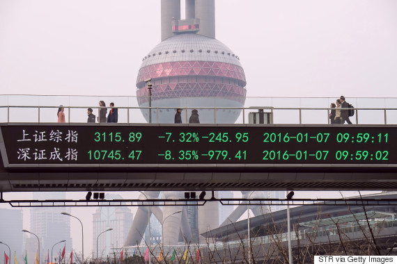 People walk along a pedestrian bridge with a screen showing Chinese stock prices crashing Shanghai