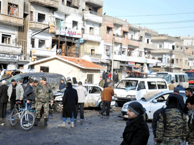 People inspect the site of a double bomb attack in the government-controlled city of Homs Syria in this handout