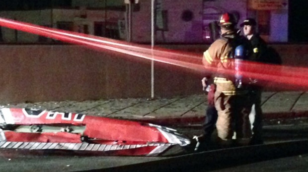 Firefighters stand near a piece of wreckage after a small plane slammed into a commercial building in downtown Anchorage Alaska early on Tuesday